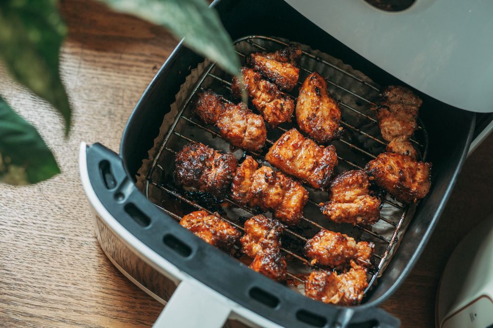 Crispy chicken and roasted food cooking in ceramic air fryer basket